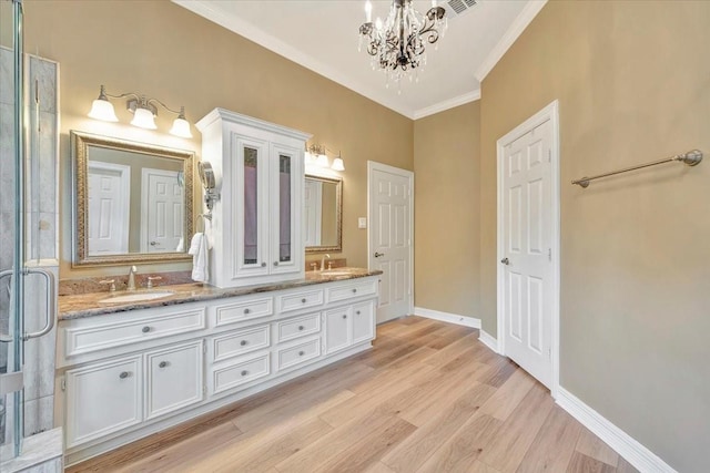 bathroom with hardwood / wood-style floors, vanity, ornamental molding, and a chandelier