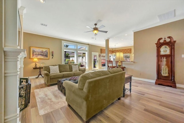 living room featuring ornate columns, ceiling fan, crown molding, and light hardwood / wood-style floors