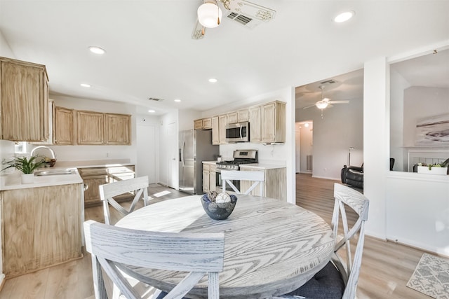 dining space featuring ceiling fan, light wood-type flooring, and sink