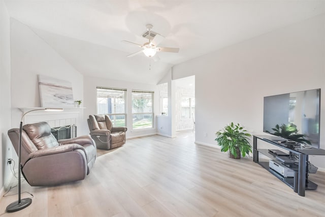 living room with a tiled fireplace, ceiling fan, light hardwood / wood-style flooring, and vaulted ceiling