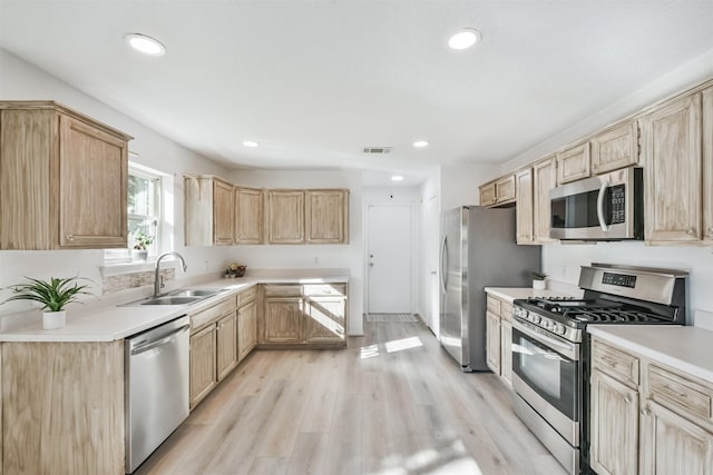 kitchen with light brown cabinets, sink, light wood-type flooring, and stainless steel appliances