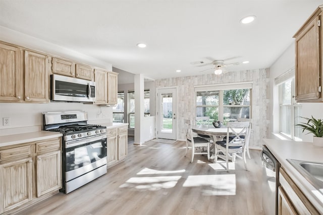 kitchen featuring appliances with stainless steel finishes, light brown cabinetry, ceiling fan, sink, and light hardwood / wood-style floors