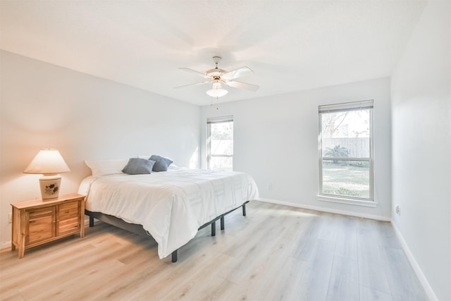 bedroom with ceiling fan, light hardwood / wood-style floors, and multiple windows