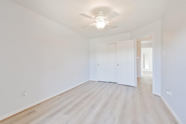 unfurnished bedroom featuring ceiling fan, a closet, and light wood-type flooring