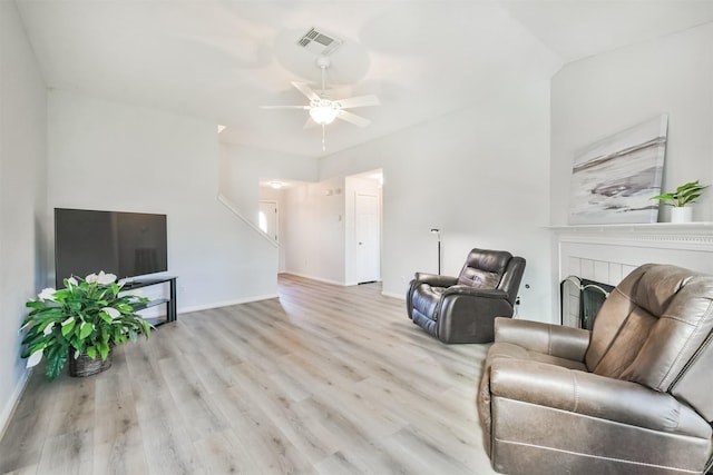 living room with a tile fireplace, light hardwood / wood-style flooring, and ceiling fan