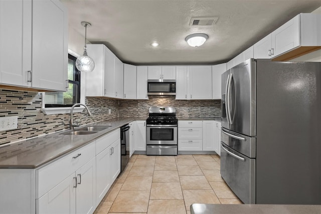 kitchen featuring light tile patterned floors, stainless steel appliances, a sink, visible vents, and backsplash