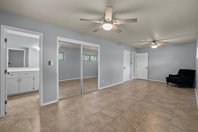 unfurnished bedroom with ceiling fan, ensuite bath, and baseboards