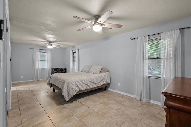 bedroom featuring a textured ceiling, light tile patterned floors, a ceiling fan, visible vents, and baseboards