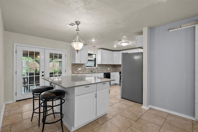 kitchen featuring white cabinets, french doors, freestanding refrigerator, a center island, and tasteful backsplash