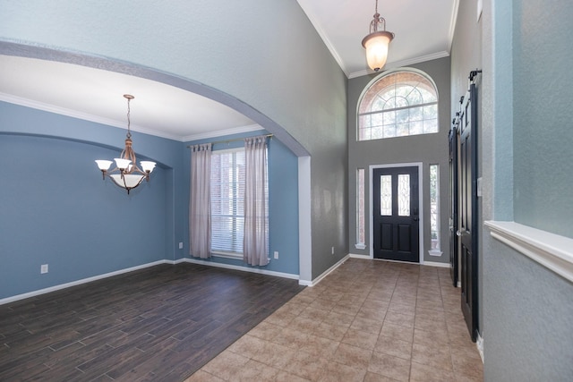 entryway featuring a barn door, crown molding, and a notable chandelier