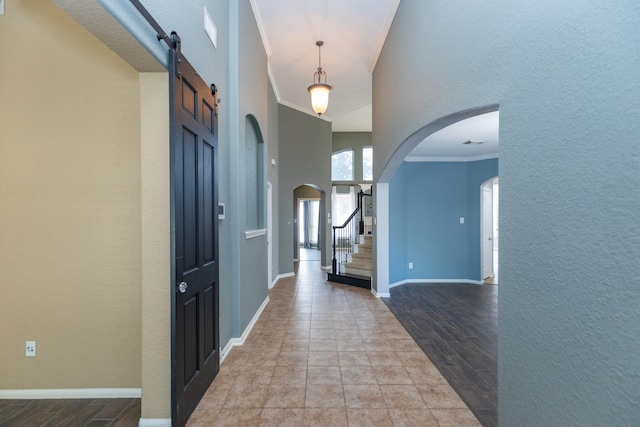 foyer with a towering ceiling, a barn door, and crown molding