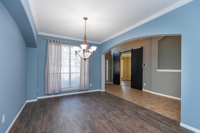 spare room with a barn door, an inviting chandelier, and ornamental molding