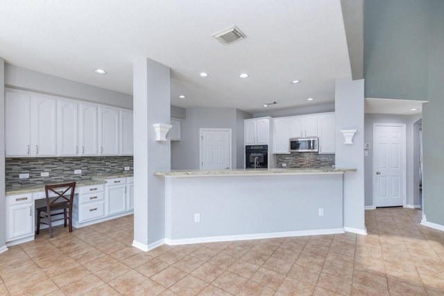 kitchen featuring light stone counters, white cabinetry, and kitchen peninsula