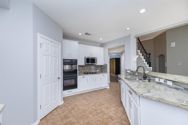 kitchen featuring white cabinets, tasteful backsplash, double oven, and sink