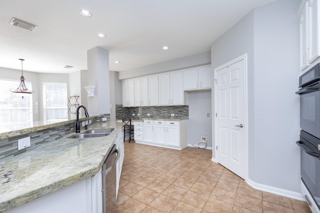 kitchen featuring white cabinetry, sink, dishwasher, hanging light fixtures, and light stone counters