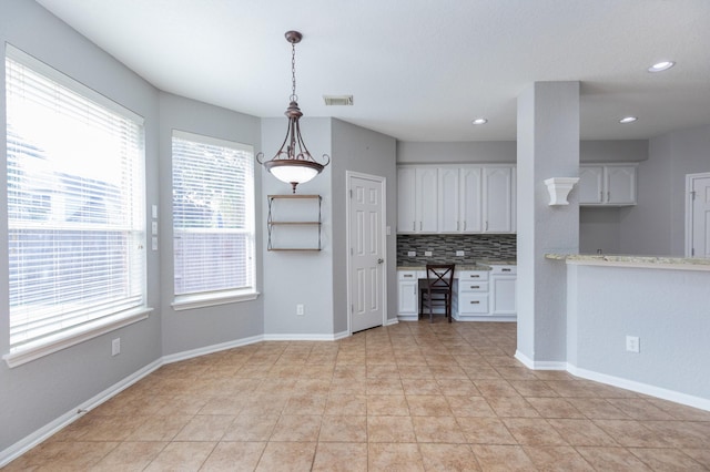 kitchen featuring a wealth of natural light, decorative backsplash, white cabinets, and pendant lighting