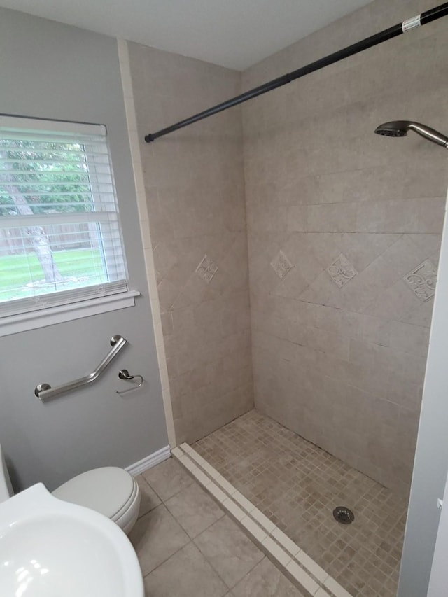 bathroom with tile patterned floors, toilet, and tiled shower