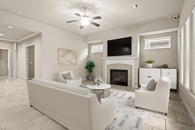 living room with ceiling fan, a tile fireplace, and a wealth of natural light