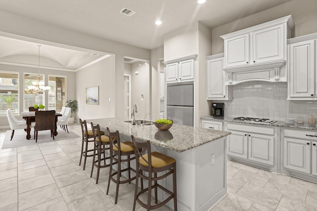 kitchen featuring a chandelier, a center island with sink, stainless steel appliances, sink, and white cabinetry