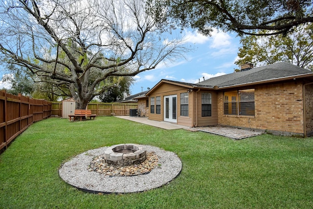 rear view of house featuring a yard, a shed, a fire pit, and a patio area