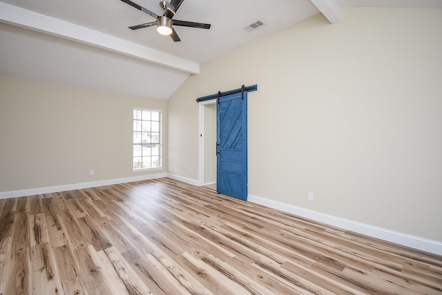 empty room featuring a barn door, ceiling fan, vaulted ceiling with beams, and light wood-type flooring