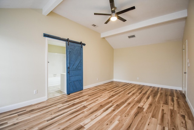 empty room with a barn door, hardwood / wood-style flooring, ceiling fan, and vaulted ceiling with beams