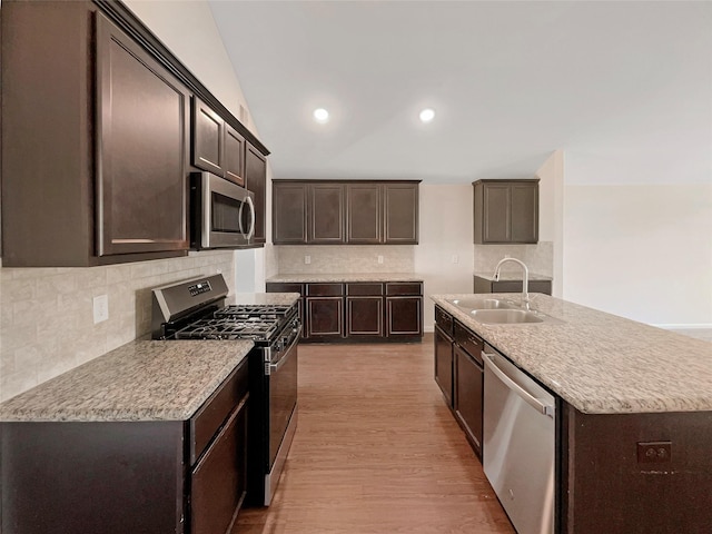 kitchen featuring a center island with sink, sink, light hardwood / wood-style flooring, dark brown cabinets, and stainless steel appliances