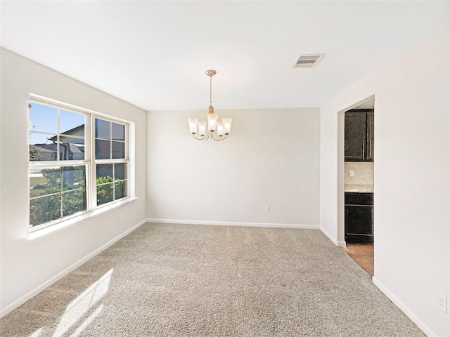 empty room featuring light carpet and a notable chandelier