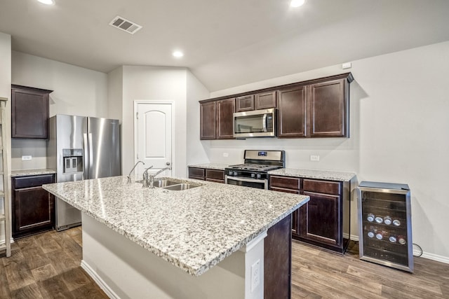 kitchen with wine cooler, sink, stainless steel appliances, and a kitchen island with sink