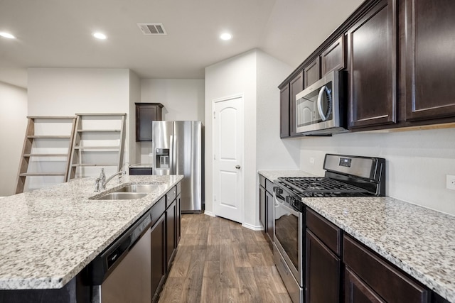 kitchen featuring a center island with sink, sink, dark hardwood / wood-style floors, light stone countertops, and appliances with stainless steel finishes