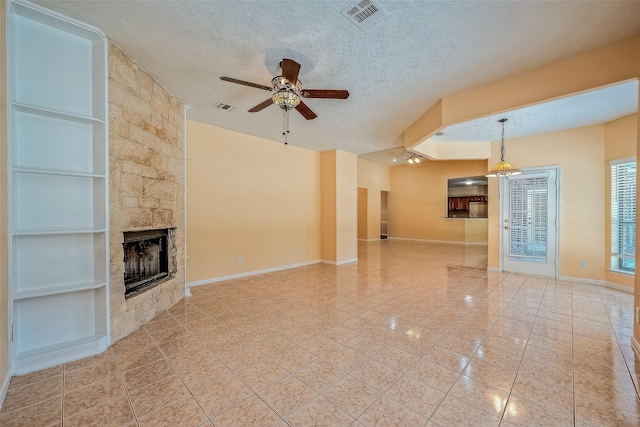 unfurnished living room featuring a fireplace, a textured ceiling, built in features, and ceiling fan