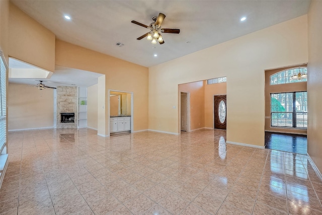 unfurnished room featuring a fireplace, a high ceiling, and ceiling fan