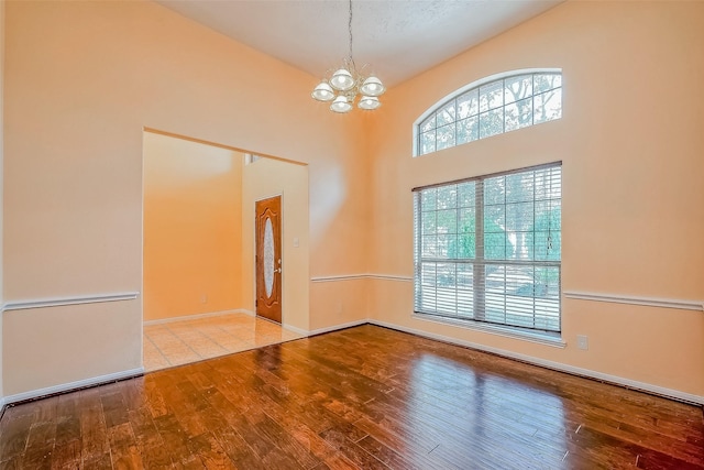 empty room with light wood-type flooring and a notable chandelier