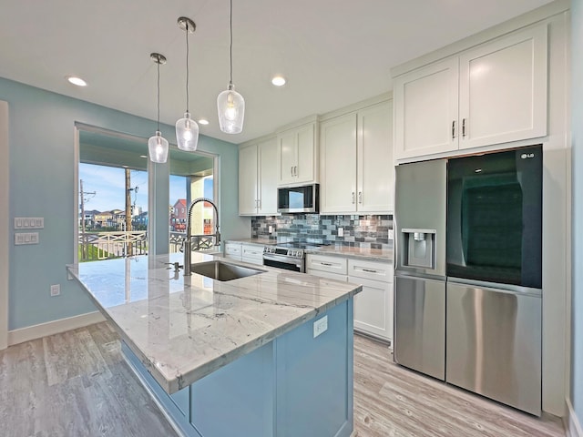 kitchen with appliances with stainless steel finishes, backsplash, sink, a center island with sink, and white cabinets