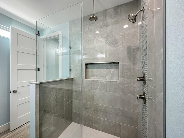 bathroom with tiled shower and wood-type flooring