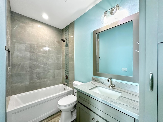 full bathroom with tiled shower / bath combo, toilet, wood-type flooring, and vanity