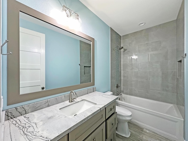 full bathroom featuring hardwood / wood-style floors, vanity, toilet, and tiled shower / bath