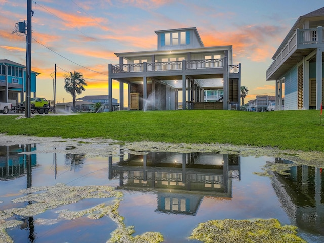 back house at dusk featuring a lawn