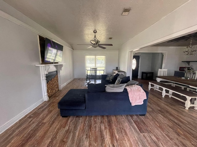 living room with ceiling fan with notable chandelier, a textured ceiling, and dark hardwood / wood-style flooring