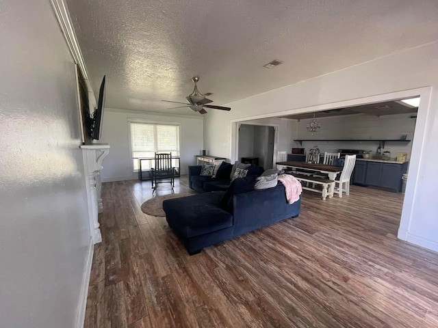 living room with dark wood-type flooring, ceiling fan, a fireplace, and a textured ceiling