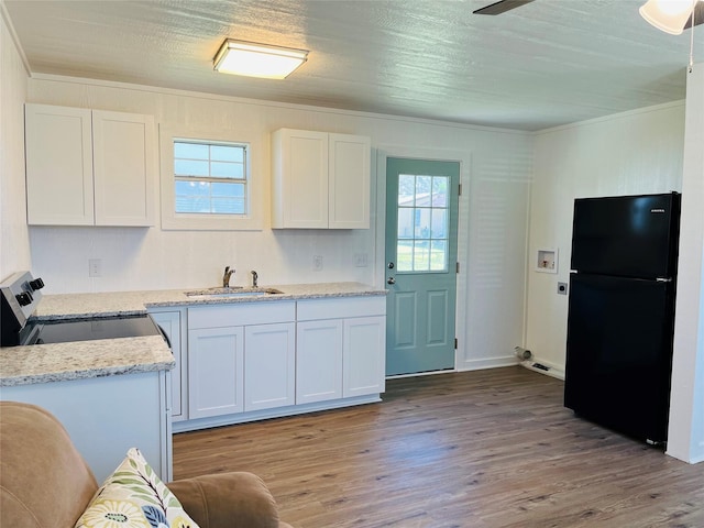 kitchen featuring sink, white cabinetry, stainless steel range with electric stovetop, light hardwood / wood-style floors, and black fridge