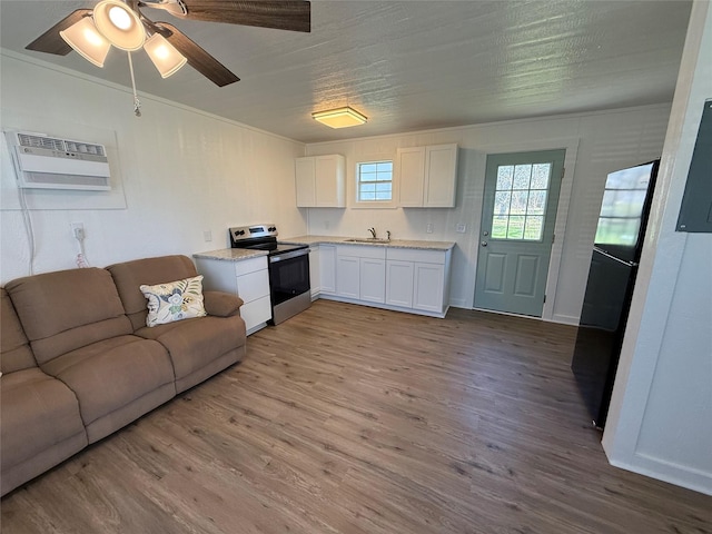 living room featuring ceiling fan, sink, a wall unit AC, and light hardwood / wood-style flooring