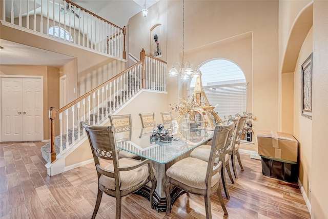 dining room with a notable chandelier, wood-type flooring, and a high ceiling