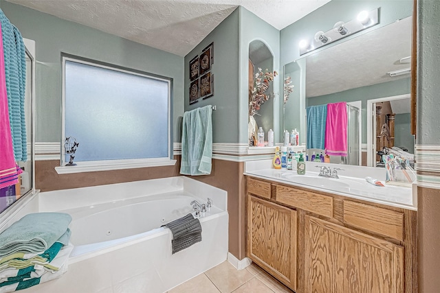 bathroom with tile patterned flooring, vanity, a textured ceiling, and a tub