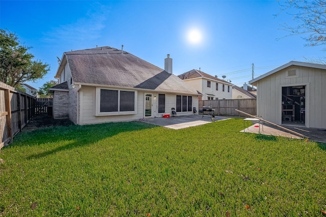 rear view of property featuring a lawn, a patio area, and a storage unit