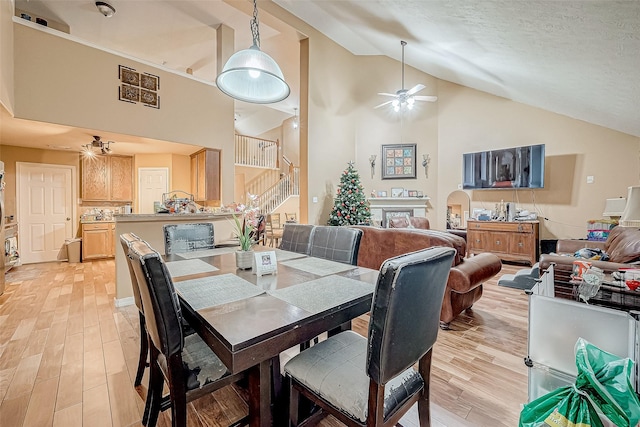 dining area featuring a textured ceiling, light hardwood / wood-style flooring, ceiling fan, and lofted ceiling