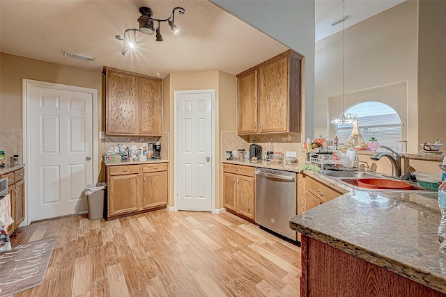 kitchen with dishwasher, sink, hanging light fixtures, tasteful backsplash, and light wood-type flooring