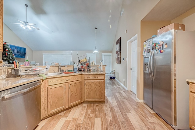 kitchen with pendant lighting, lofted ceiling, sink, light hardwood / wood-style flooring, and stainless steel appliances