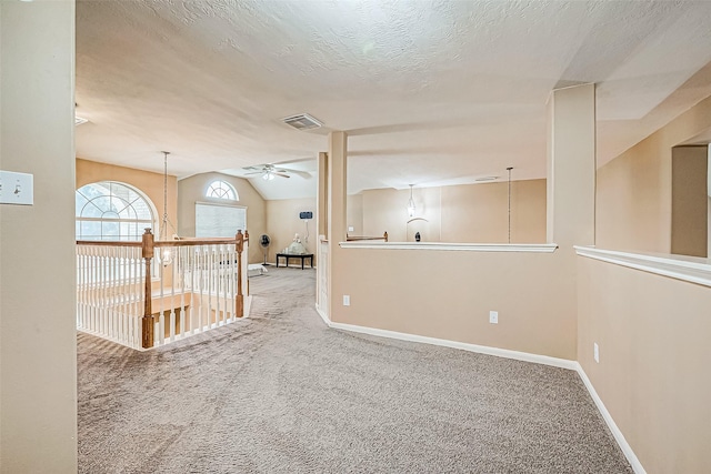 unfurnished room featuring a textured ceiling, carpet floors, vaulted ceiling, and ceiling fan