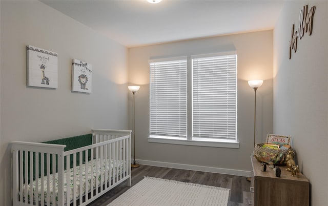 bedroom featuring a nursery area and dark hardwood / wood-style floors